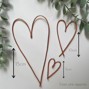 May include: Three copper wire heart shapes of varying sizes. The largest heart measures approximately 15cm tall, the medium heart is 10cm tall, and the smallest is 5cm tall. The text "Sizes are approx" is at the bottom. Decorative home decor.