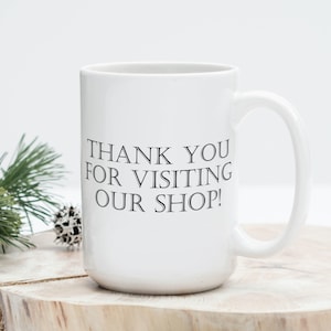 May include: White ceramic coffee mug with black text that reads "Thank you for visiting our shop!"