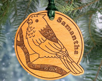 May include: A wooden Christmas ornament with a bird design and the name Samantha engraved on it. The ornament also includes the date 11.05.2024.