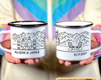 May include: Two white enamel mugs with black rims. One mug features a couple snowboarding in a mountain scene with the text "Alison & James". The other mug features a mountain scene with a ski lift and two chairs with the date "01.17.2027".