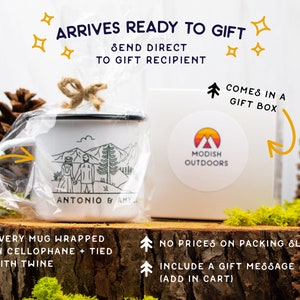 May include: A white enamel mug with a black rim and handle. The mug has a black and white illustration of a couple standing in front of mountains with the text "Antonio & Amy". The mug is wrapped in cellophane and tied with twine. The mug is in a white gift box with a sticker that says "Modish Outdoors".