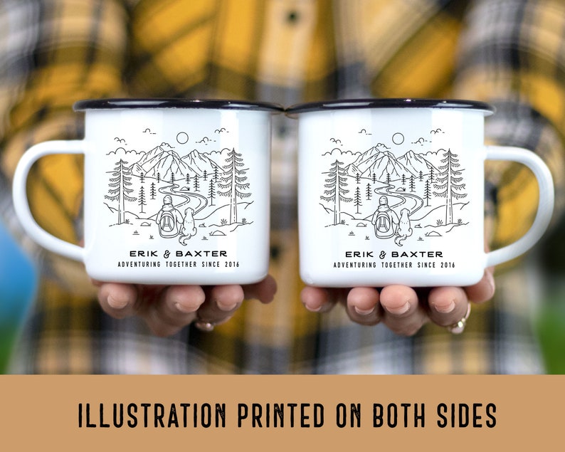 May include: Two white enamel mugs with black rims. Each mug features a black line drawing of a person and a dog walking through a forest with mountains in the background. The text "ERIK & BAXTER ADVENTURING TOGETHER SINCE 2016" is printed on the bottom of each mug.