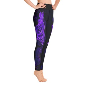May include: Black yoga leggings with a purple rabbit design. The rabbit is outlined in a neon purple color and has a swirling pattern. The leggings have a high waist.