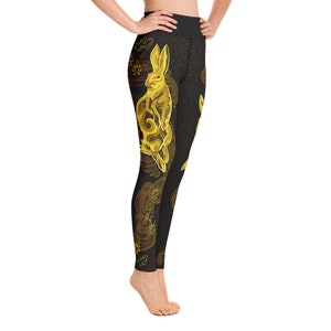 Könnte beinhalten: Schwarze Yoga-Leggings mit goldenem Design eines Kaninchens und Wolken.