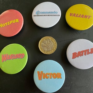 May include: Six round, colourful buttons with different words printed on them. The words are "Hotspur", "Warlord", "Victor", "Battle", "Valiant", and "Commando for Action and Adventure".