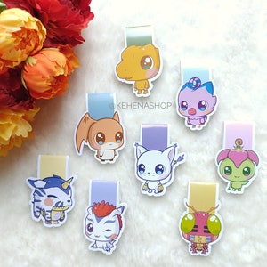 May include: Set of eight colorful magnetic bookmarks featuring various cartoon characters from the Digimon anime series. The bookmarks are printed on white cardstock and have a magnetic strip on the back.