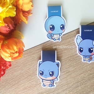 Puede incluir: Tres marcadores de personajes de dibujos animados azules y blancos con Squirtle, un Pokémon de tipo agua. Los marcadores están impresos con el texto "@kehienashp" y "kehienashp".