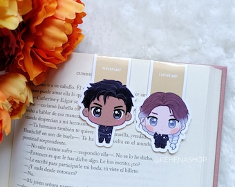 Op de afbeelding: Twee geïllustreerde bladwijzers met chibi-achtige personages. De bladwijzer aan de linkerkant toont een mannelijk personage met een donkere huidskleur, zwart haar en een zwart-blauwe outfit. De bladwijzer aan de rechterkant toont een vrouwelijk personage met een lichte huidskleur, bruin haar en een zwart-witte outfit. Beide bladwijzers hebben een lichtgele achtergrond met de tekst "KEMENASHOP" erop gedrukt.