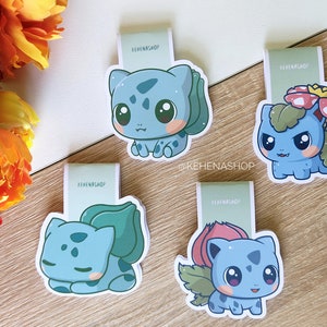 Puede incluir: Cuatro marcadores de colores con un personaje de dibujos animados con diferentes expresiones y poses. El personaje es azul con detalles verdes y una flor roja en la cabeza. Los marcadores están impresos con el texto "KEHENASHOP".
