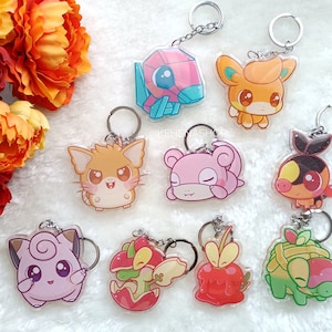 Puede incluir: Un conjunto de nueve llaveros de personajes de dibujos animados coloridos. Los llaveros presentan personajes de anime y videojuegos populares. Los llaveros están hechos de acrílico transparente y tienen un acabado brillante.