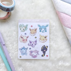 Könnte beinhalten: Ein Bogen mit Aufklebern, die verschiedene Pokémon-Charaktere zeigen, darunter Eevee, Vaporeon, Jolteon, Flareon, Espeon, Umbreon, Glaceon, Leafeon und Sylveon. Die Aufkleber befinden sich auf einem weißen Hintergrund mit einem hellblauen Rand und dem Text "Cute Evolutions" oben.