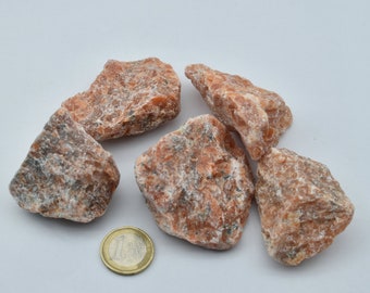 May include: A group of five rough, orange-brown, natural rock crystals. The crystals are various sizes and shapes. A single euro coin is included for scale.