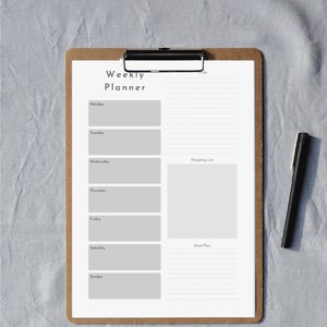 Könnte beinhalten: Ein Wochenplaner auf einer Klemmbrett mit Abschnitten für jeden Tag der Woche, einer To-Do-Liste, einer Einkaufsliste und einem Speiseplan.