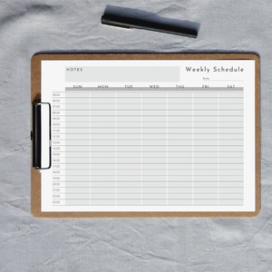 Könnte beinhalten: Ein wöchentlicher Zeitplaner auf einer Klemmbrett mit grauem Hintergrund. Der Planer hat Spalten für jeden Tag der Woche, von Sonntag bis Samstag, und Zeilen für jede Stunde des Tages, von 5:00 Uhr morgens bis 23:00 Uhr abends. Der Planer hat auch einen Bereich für Notizen.