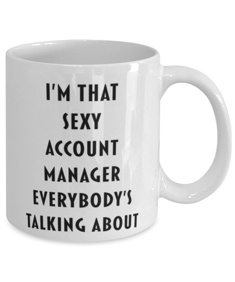 May include: White ceramic coffee mug with black text that reads "I'm that sexy account manager everybody's talking about".