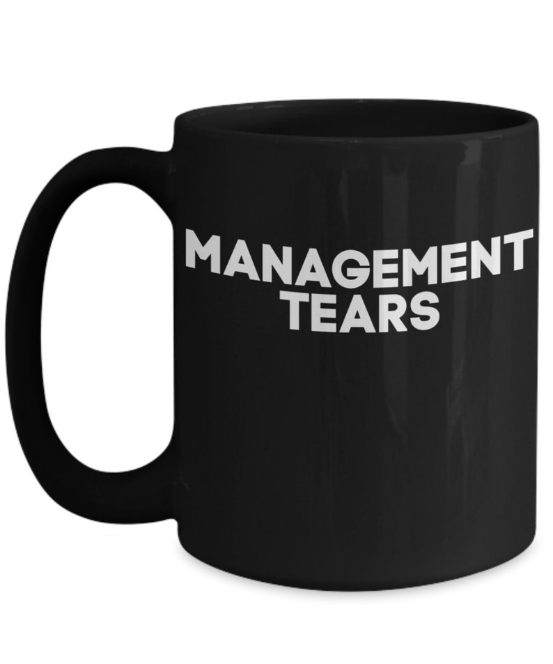 May include: Black ceramic coffee mug with white text that reads "MANAGEMENT TEARS".