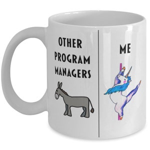 Op de afbeelding: Een witte keramische koffiemok met een zwart-witte illustratie van een ezel aan de linkerkant en een eenhoorn aan de rechterkant. De tekst "Other Program Managers" staat boven de ezel en "Me" staat boven de eenhoorn.