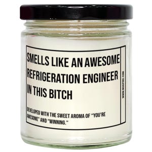 Peut inclure: Une bougie en pot de verre avec un couvercle noir. L'étiquette indique "SMELLS LIKE AN AWESOME REFRIGERATION ENGINEER IN THIS BITCH." Le bas de l'étiquette dit "DEVELOPED WITH THE SWEET AROMA OF 'YOU'RE AWESOME' AND 'WINNING.'"