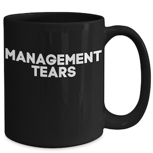 May include: Black ceramic coffee mug with white text that reads "MANAGEMENT TEARS".