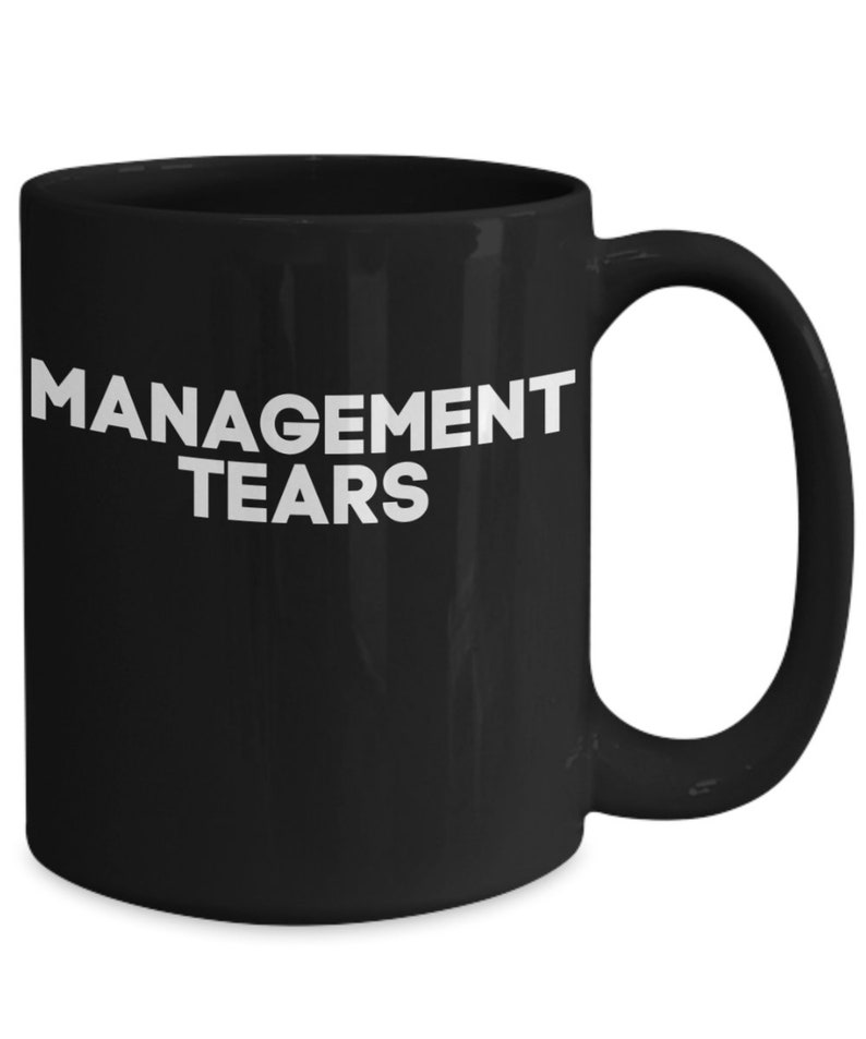 May include: Black ceramic coffee mug with white text that reads "MANAGEMENT TEARS".