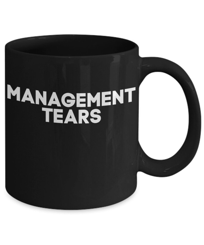 May include: Black ceramic coffee mug with white text that reads "MANAGEMENT TEARS".