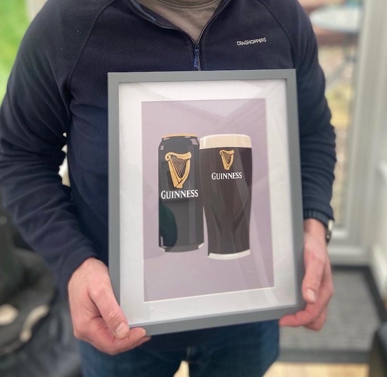 Peut inclure: Impression encadr&eacute;e repr&eacute;sentant une canette et un verre de Guinness. La canette est noire avec un logo de harpe dor&eacute;e et le mot "Guinness". Le verre est sombre avec une t&ecirc;te cr&eacute;meuse, portant &eacute;galement le logo Guinness.