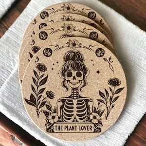 May include: Set of six cork coasters featuring a black and white illustration of a skeleton with flowers and the text "The Plant Lover".