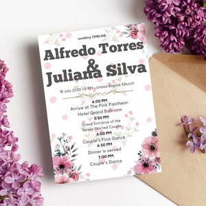 May include: A wedding invitation with the names "Alfredo Torres & Juliana Silva" in bold, black font. The invitation includes the date, time, and location. Floral accents and pink polka dots decorate the invitation. Lilac flowers and a brown envelope are also in the image.