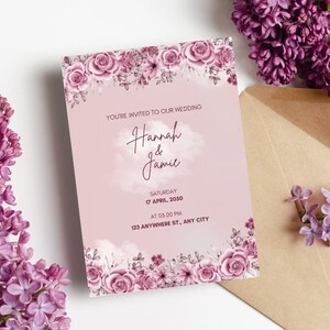 May include: A wedding invitation with floral accents and the text "You're Invited to Our Wedding" featuring the names "Hannah & Jamie". The invitation is surrounded by purple flowers and a brown envelope.