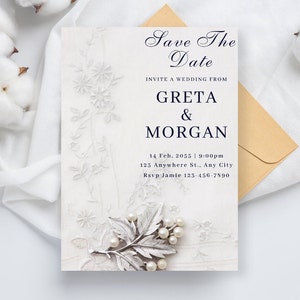 May include: A wedding invitation with the text "Save The Date" and details for Greta & Morgan's wedding. The invitation is white with floral lace and a silver leaf accent with pearls. An envelope and cotton flowers are also present.