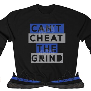 Może przedstawiać: Czarny sweter z napisem "CAN'T CHEAT THE GRIND" w niebieskich i szarych literach. Sweter jest połączony z czarnymi i niebieskimi butami sportowymi.