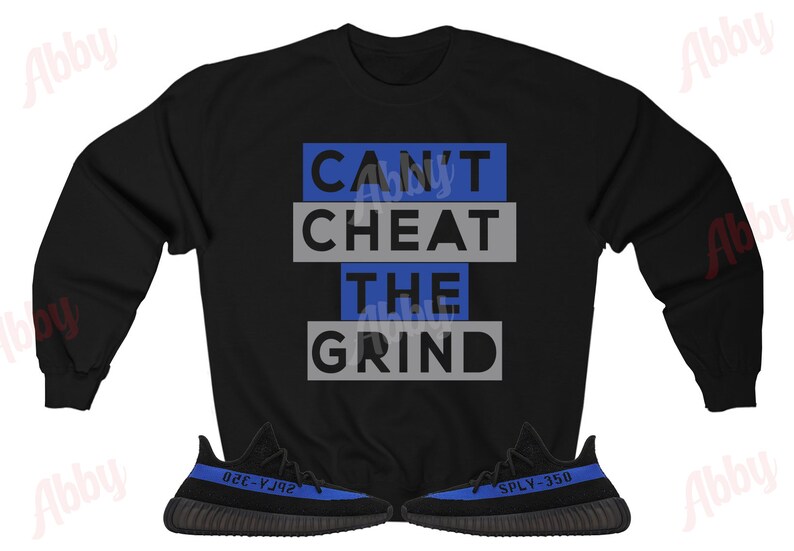 Może przedstawiać: Czarny sweter z napisem "CAN'T CHEAT THE GRIND" w niebieskich i szarych literach. Sweter jest połączony z czarnymi i niebieskimi butami sportowymi.