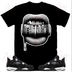 May include: Black and white graphic t-shirt featuring a pair of lips biting down on a roll of cash. The lips are dripping with a liquid substance. The t-shirt is paired with black and white sneakers.