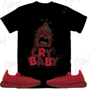 Puede incluir: Camiseta gr&aacute;fica roja y negra con un biber&oacute;n de beb&eacute; de dibujos animados llorando y el texto "CRY BABY". Un par de zapatillas Adidas Yeezy Boost 350 V2 rojas.