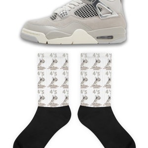 May include: A pair of gray and white sneakers with a silver accent and a pair of white socks with a gray print of the sneakers. The socks have the text "4'S" repeated on them.