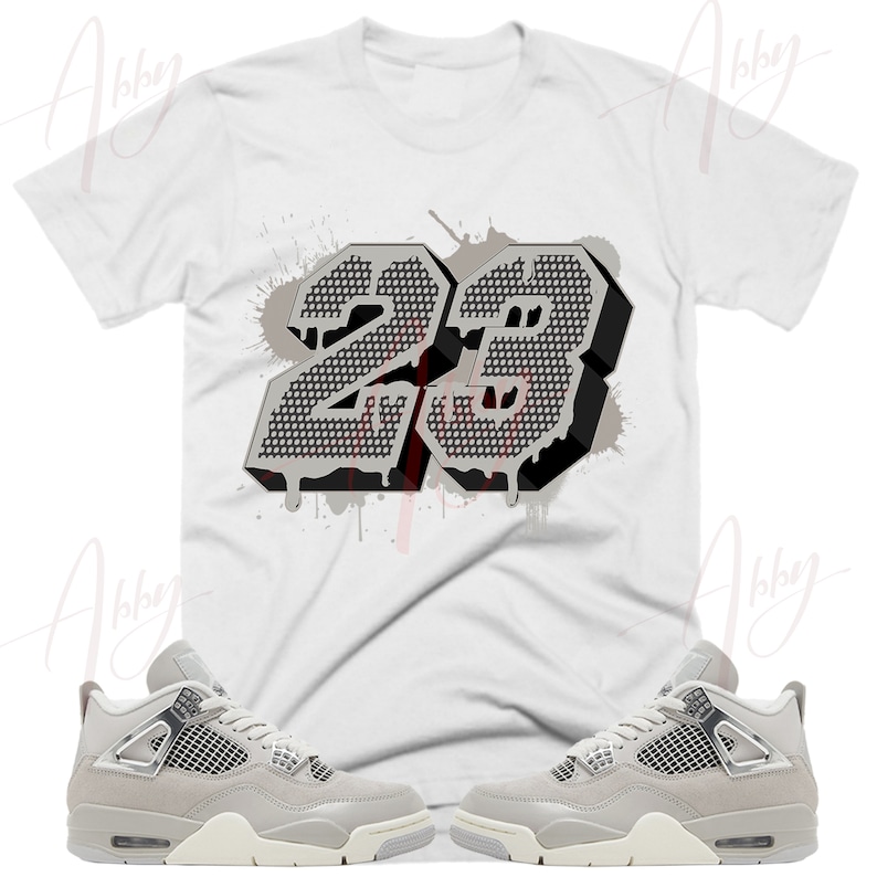 May include: A white t-shirt with a gray and black graphic of the number 23 with paint splatters. A pair of gray and white sneakers with a mesh design.