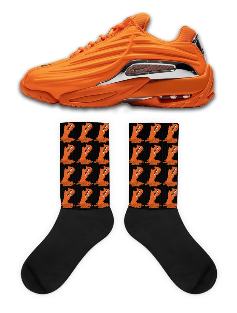 Peut inclure: Chaussures de sport orange et noires avec un accent argent&eacute; sur le c&ocirc;t&eacute;. Les chaussures sont associ&eacute;es &agrave; des chaussettes noires avec un motif r&eacute;p&eacute;t&eacute; de chaussures de sport orange.