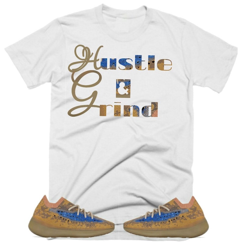 May include: White t-shirt with the text "Hustle & Grind" in gold and blue lettering. A pair of brown and blue trainers with a speckled pattern.