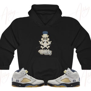 May include: Black hoodie with a cartoon character wearing a hat and the word "Haters" in a stylized font. Two pairs of white and blue sneakers with black soles.
