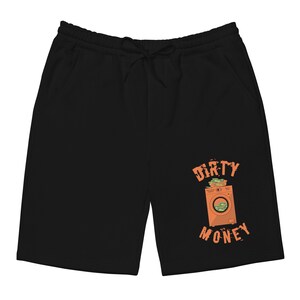 Peut inclure: Pantalon de surv&ecirc;tement noir avec un graphique d'une machine &agrave; laver contenant de l'argent et le texte "Dirty Money" en orange.