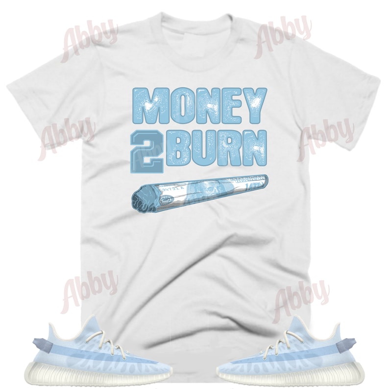 May include: White t-shirt with blue text that says "Money 2 Burn" and a blue image of a rolled-up dollar bill.  The t-shirt is paired with light blue sneakers with white soles.