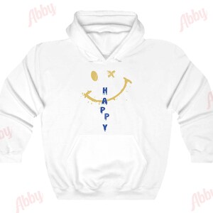 May include: White hoodie with a gold smiley face and the word "HAPPY" written vertically in blue letters.