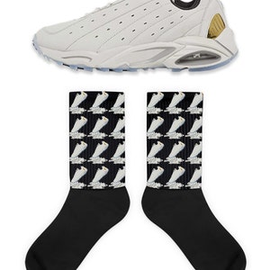 May include: White sneakers with a black and gold accent on the back. The sneakers are paired with black socks that have a repeating pattern of the white sneakers on a black background.