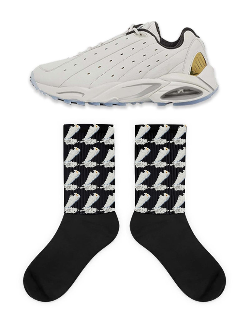 May include: White sneakers with a black and gold accent on the back. The sneakers are paired with black socks that have a repeating pattern of the white sneakers on a black background.