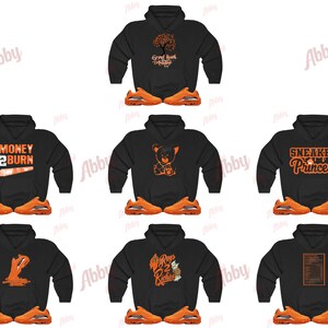 May include: Several black hoodies with orange designs and text, such as "Money 2 Burn" and "Sneaker Princess." Each hoodie is displayed with a pair of orange trainers, presenting a coordinated streetwear style.
