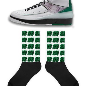 May include: White and green high-top sneakers with a white wing design on the side. The sneakers are paired with white socks with a green repeated pattern of the number "23".