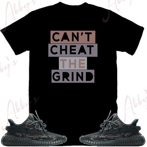 May include: Black t-shirt with the text "Can't Cheat The Grind" in brown and grey lettering. A pair of black and green camouflage sneakers are also pictured.