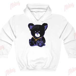 May include: White hoodie with a black bear wearing a gold chain. The bear has a blue outline and a grumpy expression.