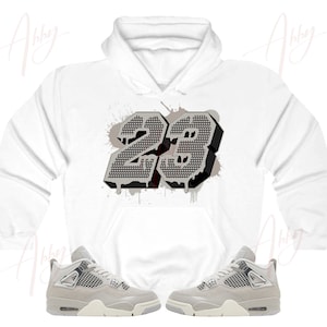 May include: White hoodie with a gray and black number 23 graphic print. The hoodie is paired with gray and white sneakers.