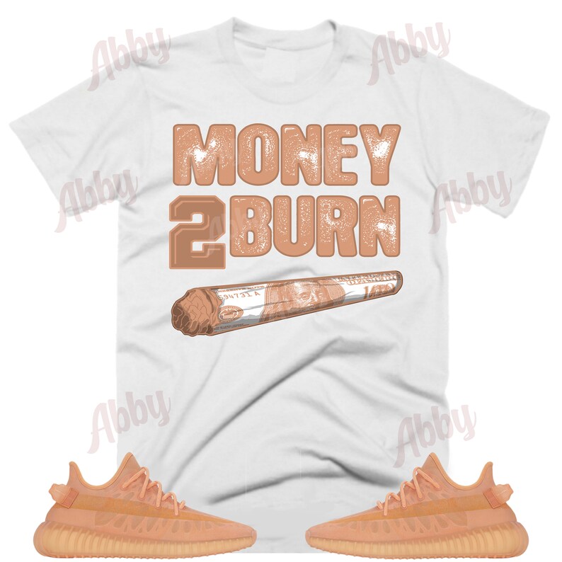 May include: A white t-shirt with the text "MONEY 2 BURN" in brown lettering and a brown image of a rolled-up dollar bill. The t-shirt is paired with two pairs of tan trainers.